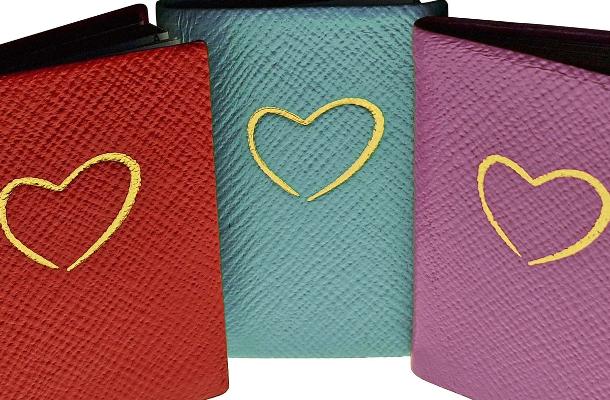Three coloured leather notebooks with gold heart embossing on textured covers