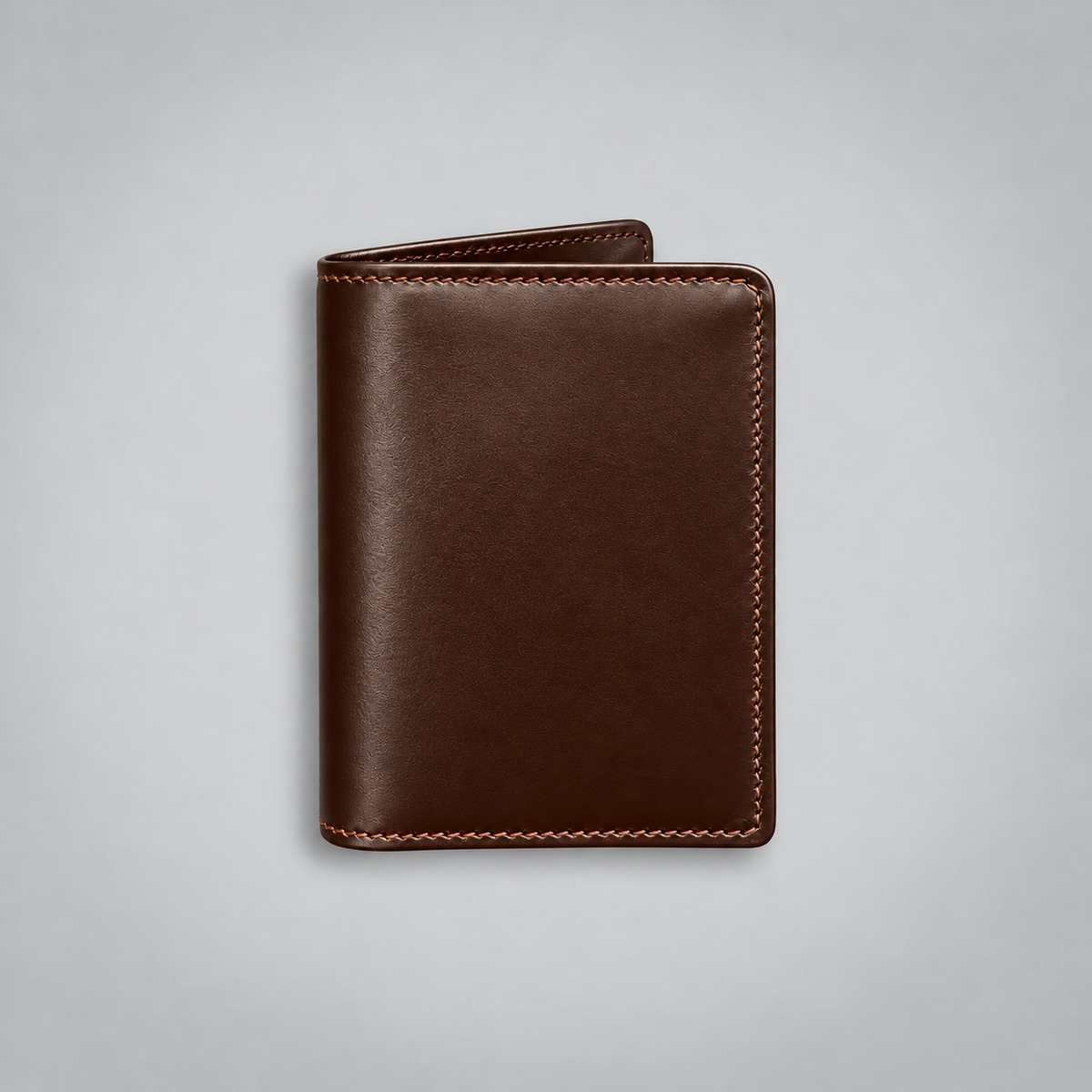 A dark brown leather card holder wallet with light tan stitching, shown closed on a light gray background.