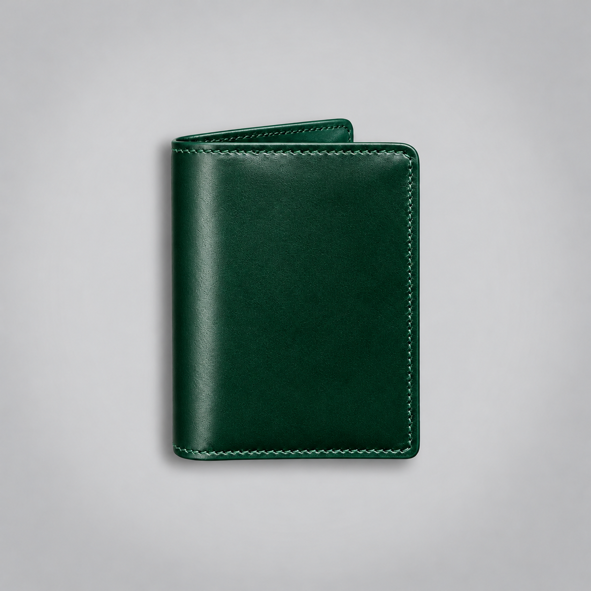 A dark green leather business card holder or slim wallet with matching stitching, shown closed on a neutral light gray background.
