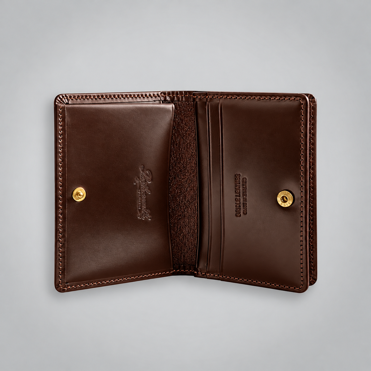 An open dark brown leather wallet shown flat against a light gray background, featuring gold snap buttons, card slots, and embossed branding.
