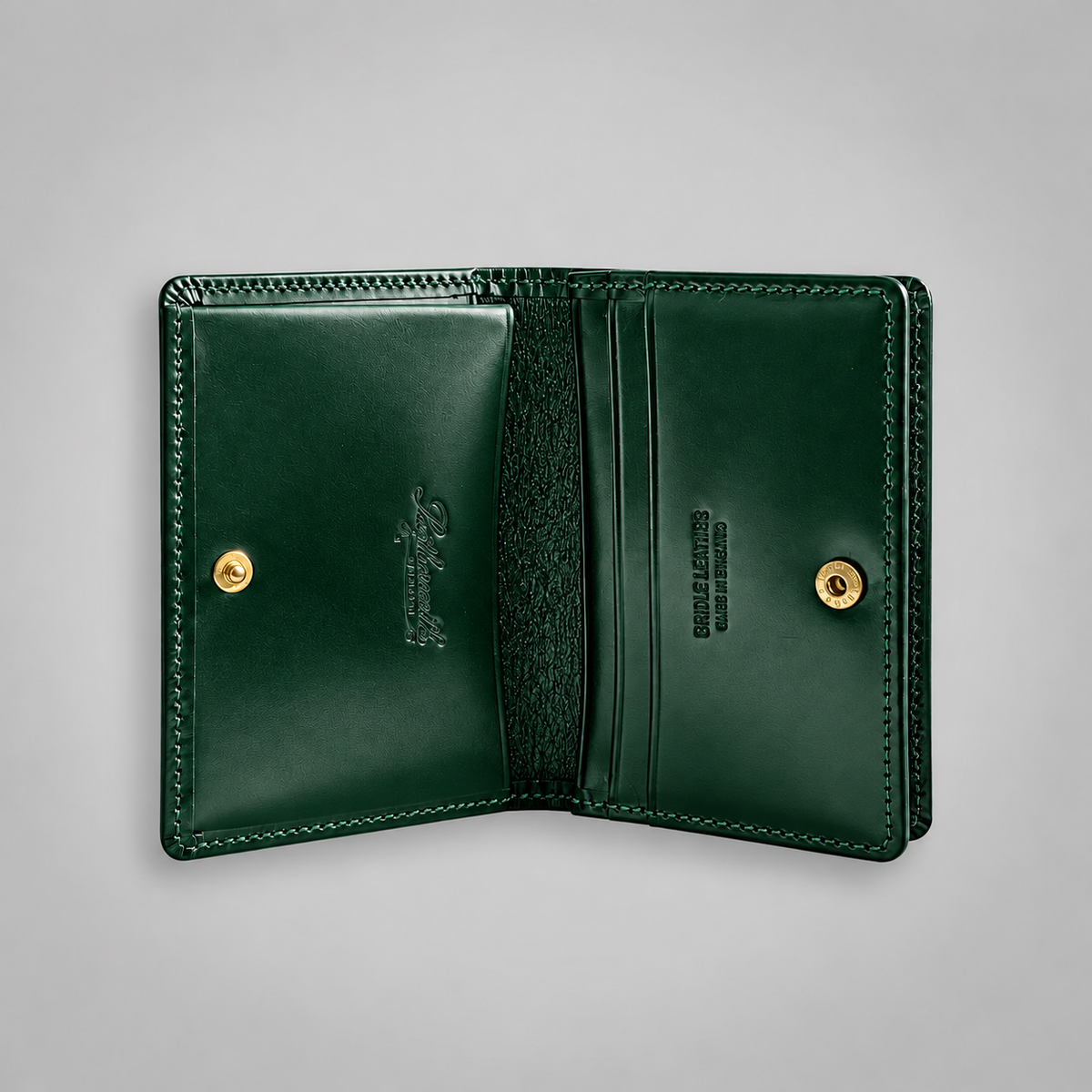 An open dark green leather wallet with gold-tone snap buttons, showing interior card slots, stitching, and branding on a light gray background.